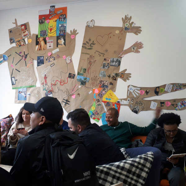 Groupe de jeunes devant une créature culturelle en papier et collage affiché sur le mur